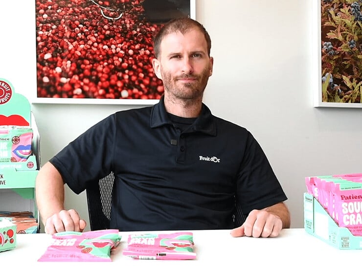 Fruit d’Or Product Specialist René-Junior Turcotte sits at a desk with Fruit d'Or products around him